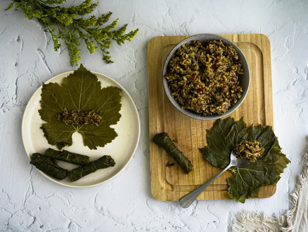 Dolma on a plate next to a cutting board with dolma ingredients
