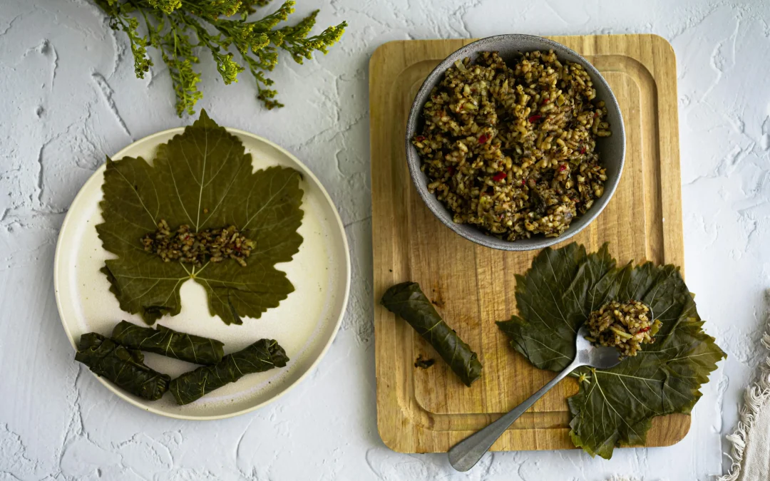 Dolma on a plate next to a cutting board with dolma ingredients