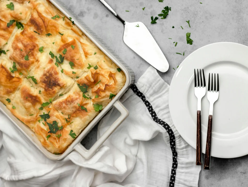 Spanakopita in a baking dish next to a plate